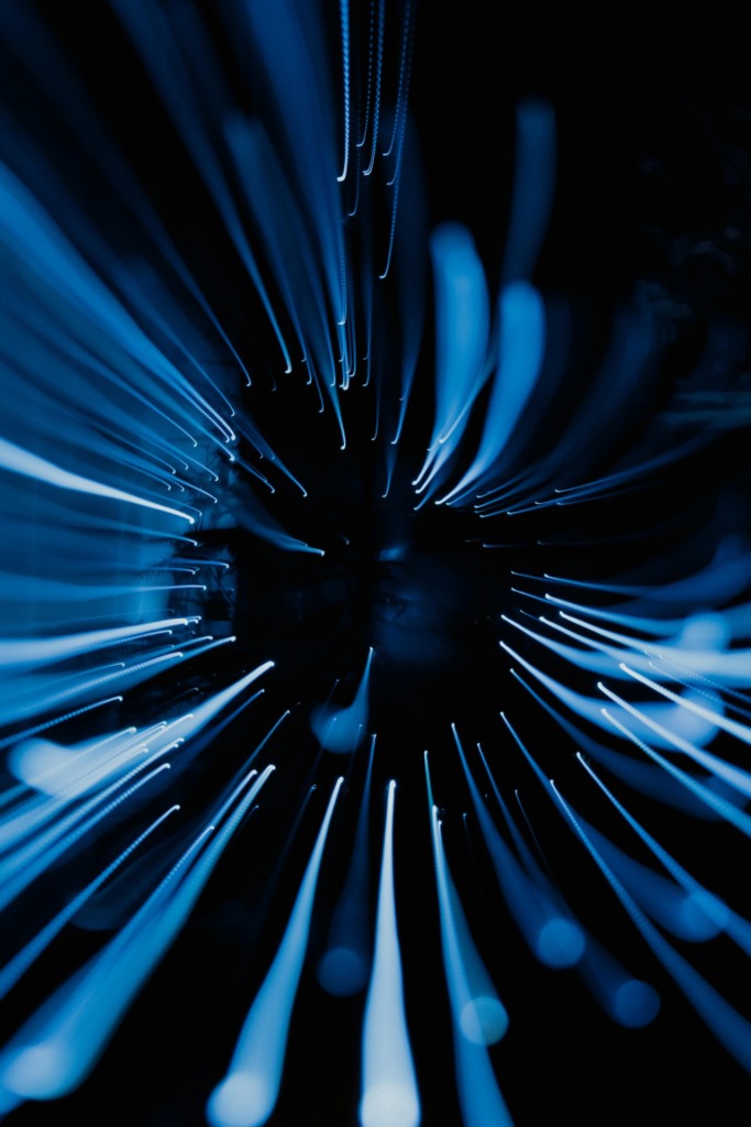 Dynamic abstract image showcasing blue light streaks captured in motion with a dark background.